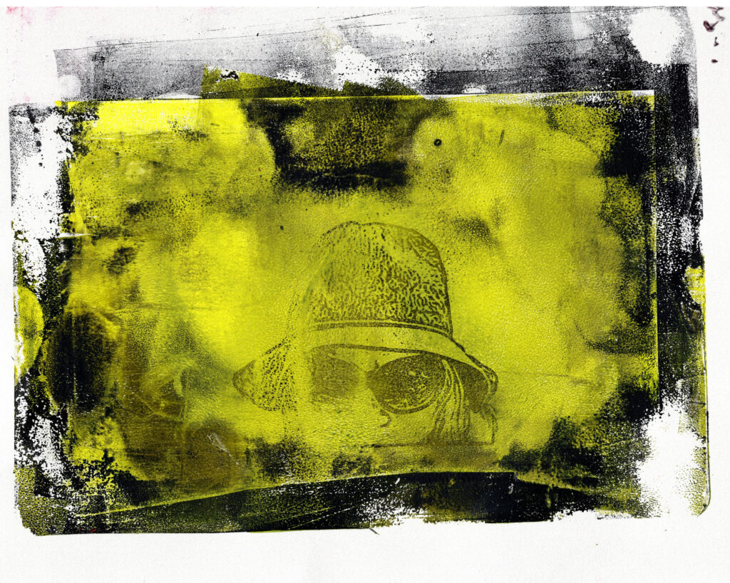 An abstract yellow and black gel plate print. A distressed, grungy black border frames a vibrant yellow center, which reveals a faded, surrealistic portrait of a woman wearing a bucket hat and sunglasses.
